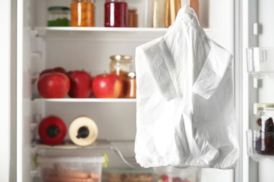 Many plastic bags near refrigerator with products. Space for text