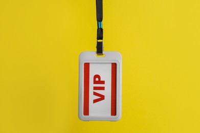 Photo of White plastic vip badge hanging on yellow background