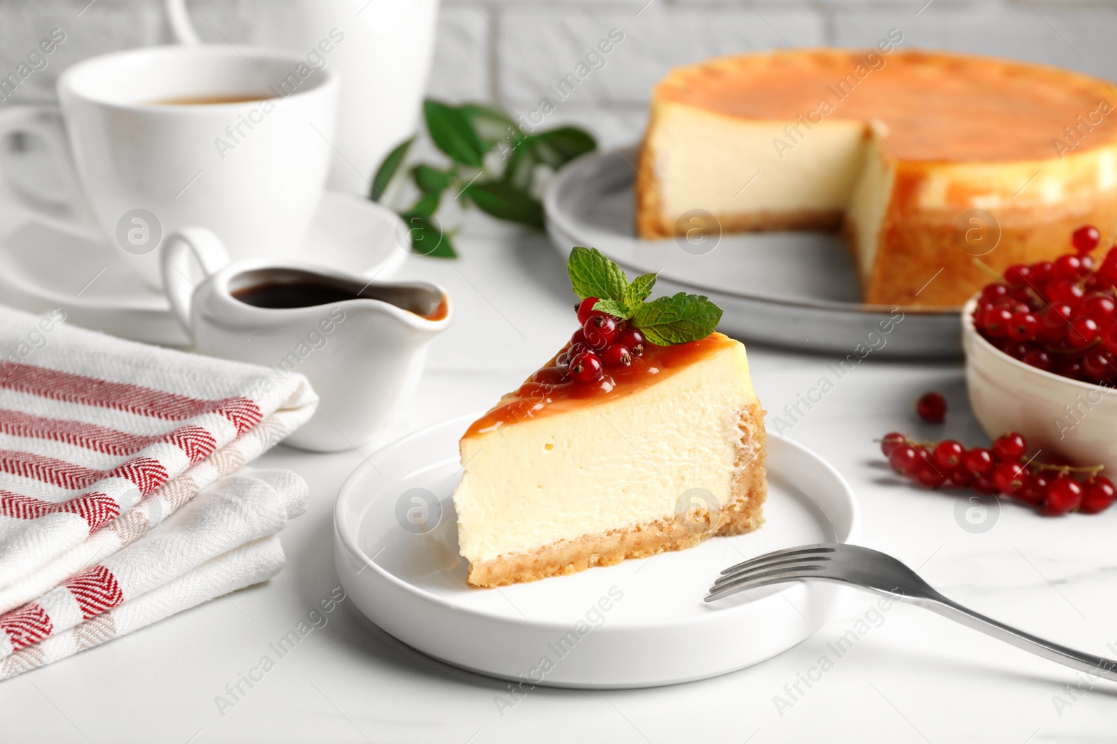 Photo of Piece of delicious caramel cheesecake with red currants and mint served on white marble table