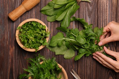 Photo of Woman with fresh green herbs at wooden table, top view