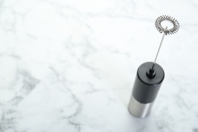 Photo of Black milk frother wand on white marble table. Space for text