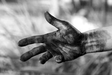 Photo of Dirty worker on blurred background, closeup of hand. Black and white effect