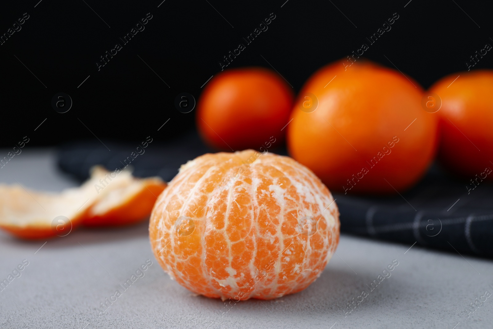 Photo of Peeled ripe tangerine on grey table, closeup