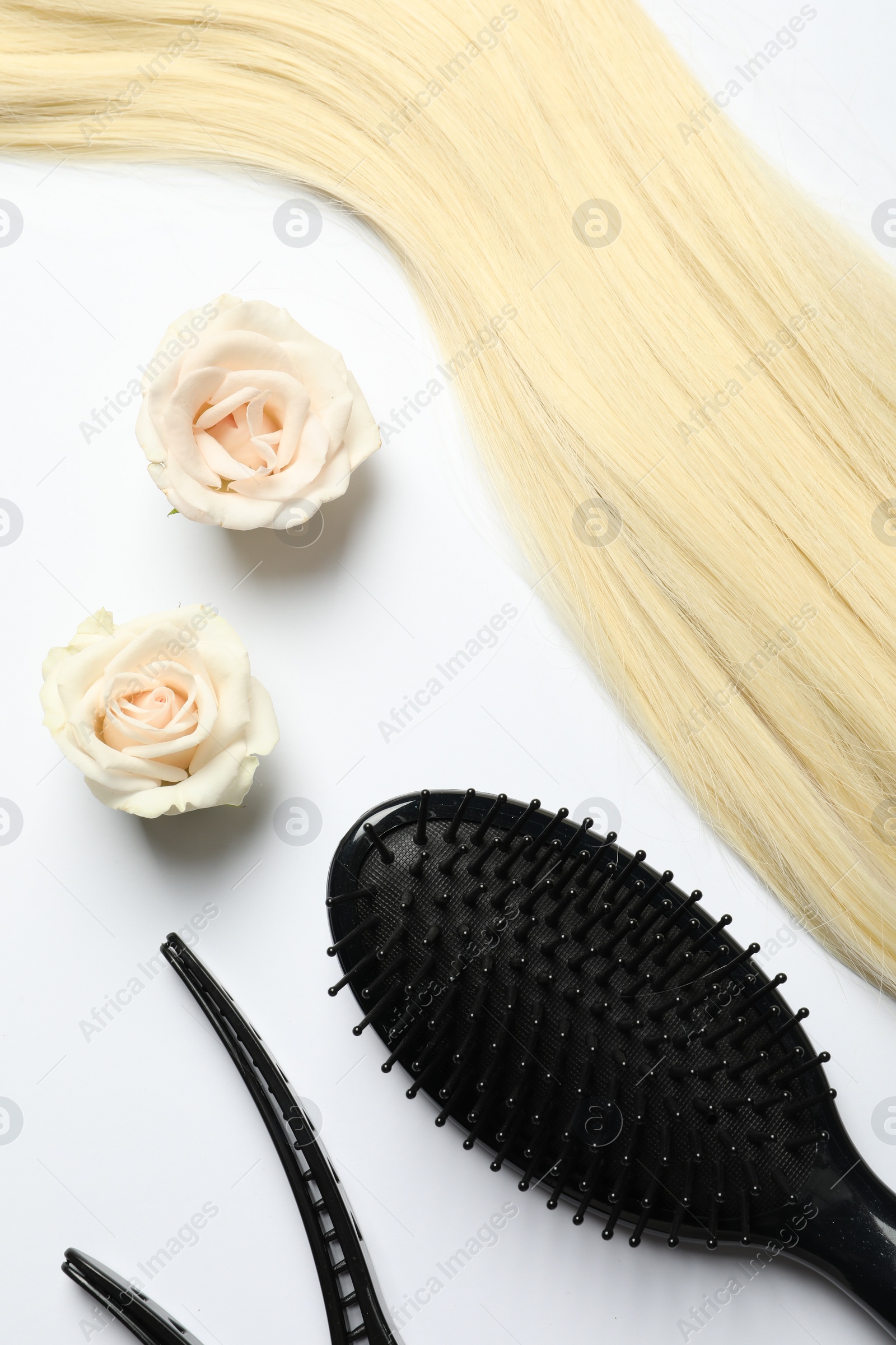 Photo of Hairdresser tools. Blonde hair lock, clips, brush and flowers on white backpack, flat lay