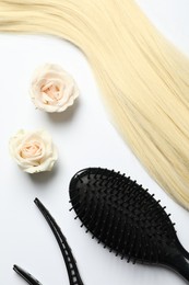 Photo of Hairdresser tools. Blonde hair lock, clips, brush and flowers on white backpack, flat lay