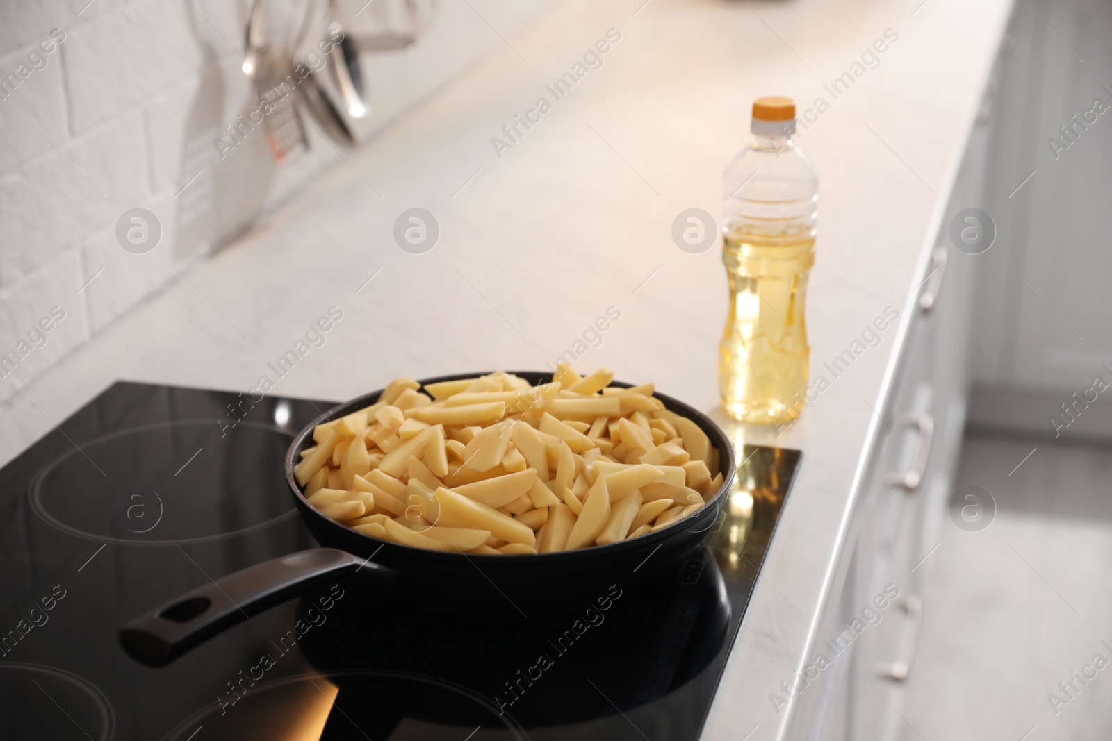 Photo of Frying pan with cut raw potatoes on cooktop