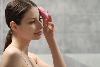 Washing face. Young woman with cleansing brush indoors, space for text