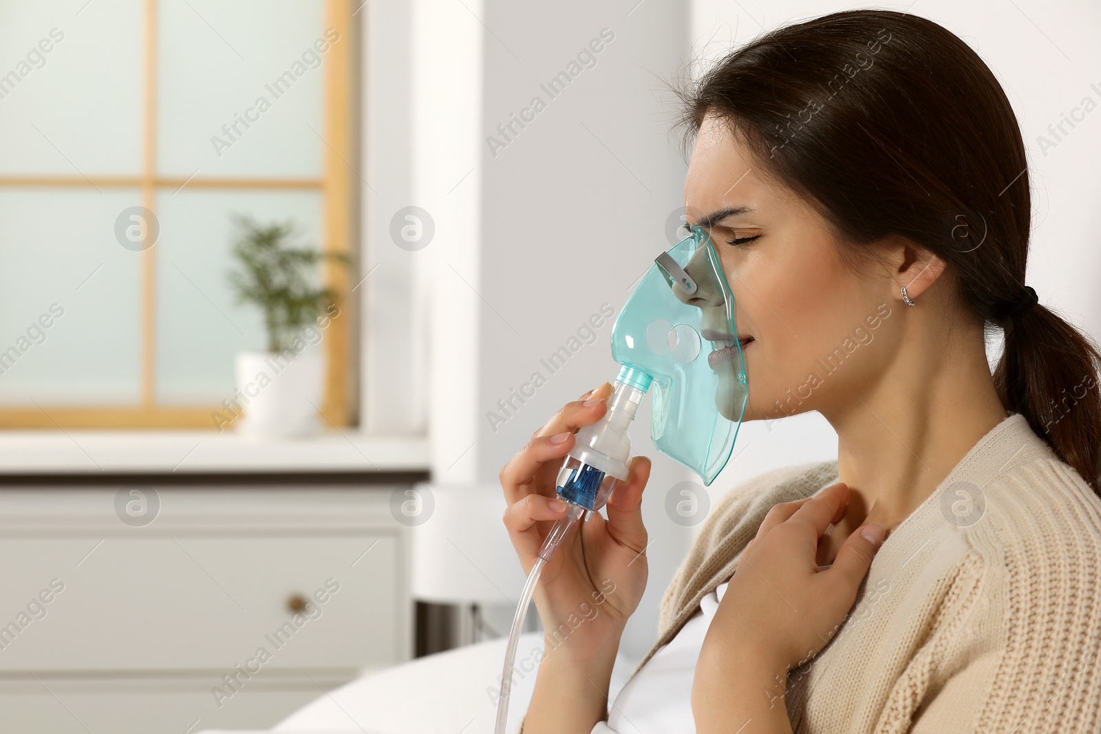 Photo of Sick young woman using nebulizer at home, space for text