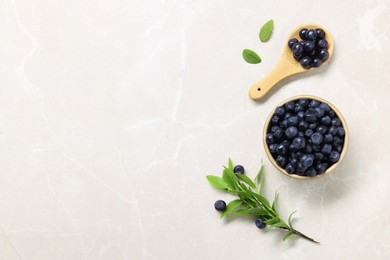 Bowl of tasty fresh bilberries and green leaves on white table, flat lay. Space for text