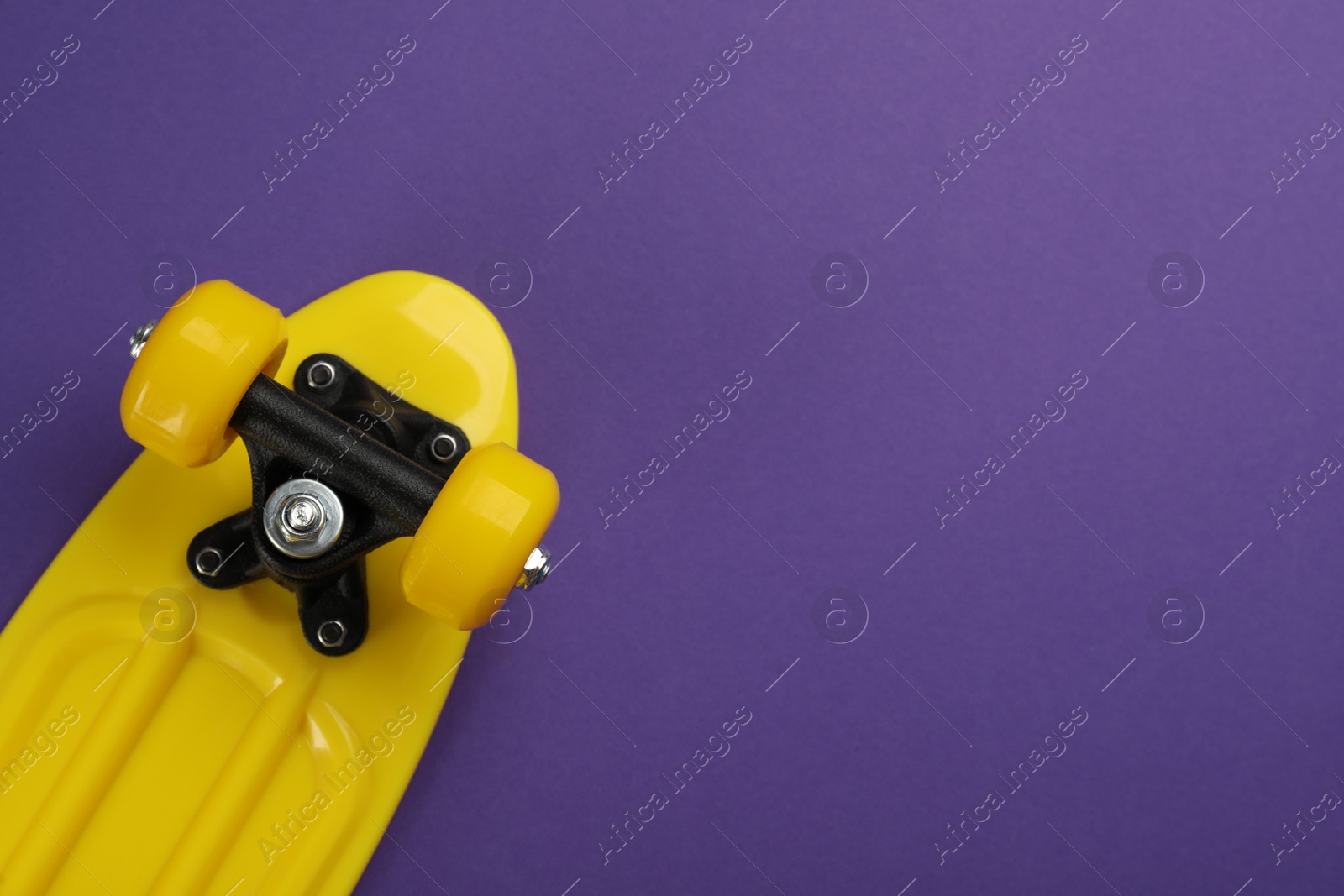 Photo of Skateboard on purple background, top view. Space for text