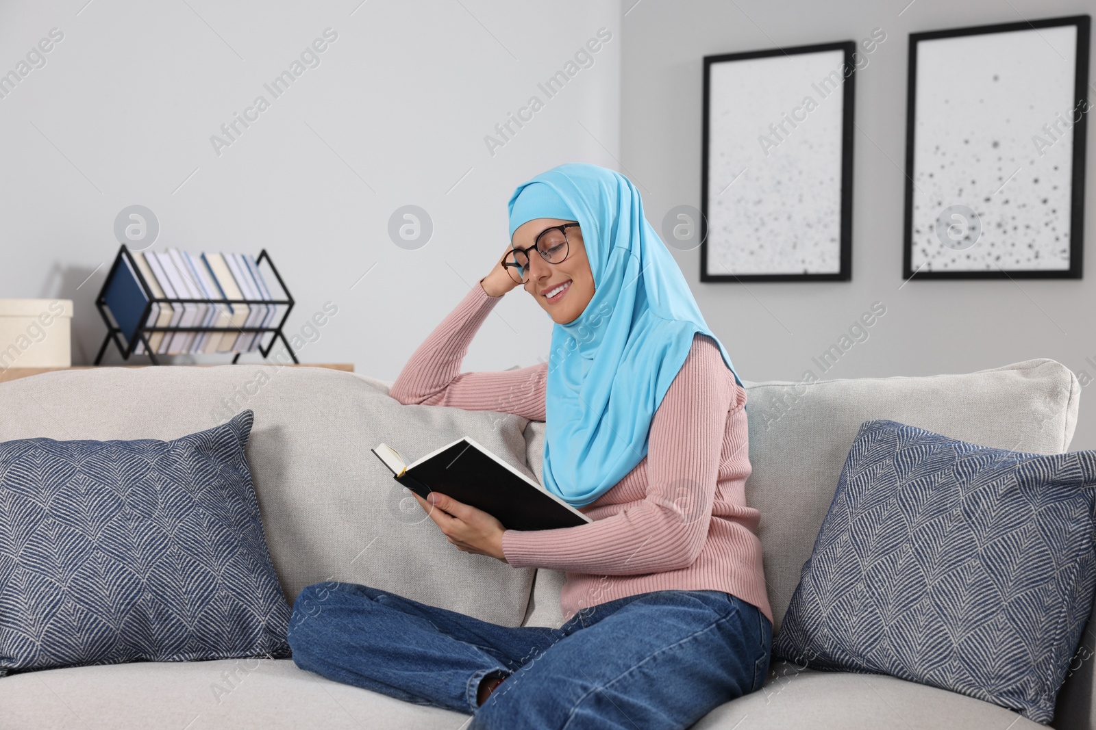 Photo of Muslim woman reading book on couch in room