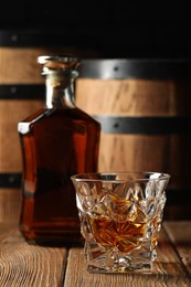 Photo of Glass and bottle of tasty whiskey on wooden table