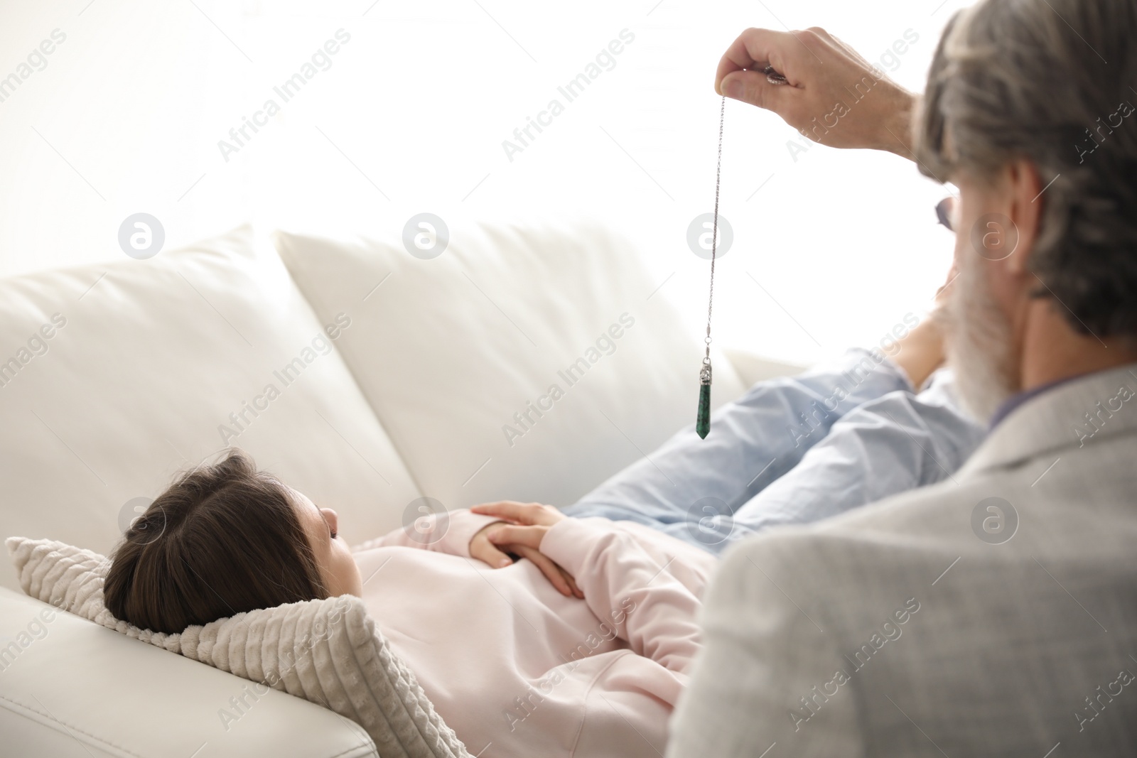 Photo of Psychotherapist using pendulum during hypnotherapy   session in office