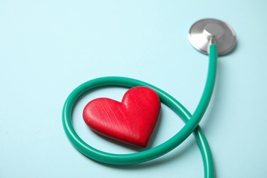 Stethoscope and red heart on color background. Cardiology concept