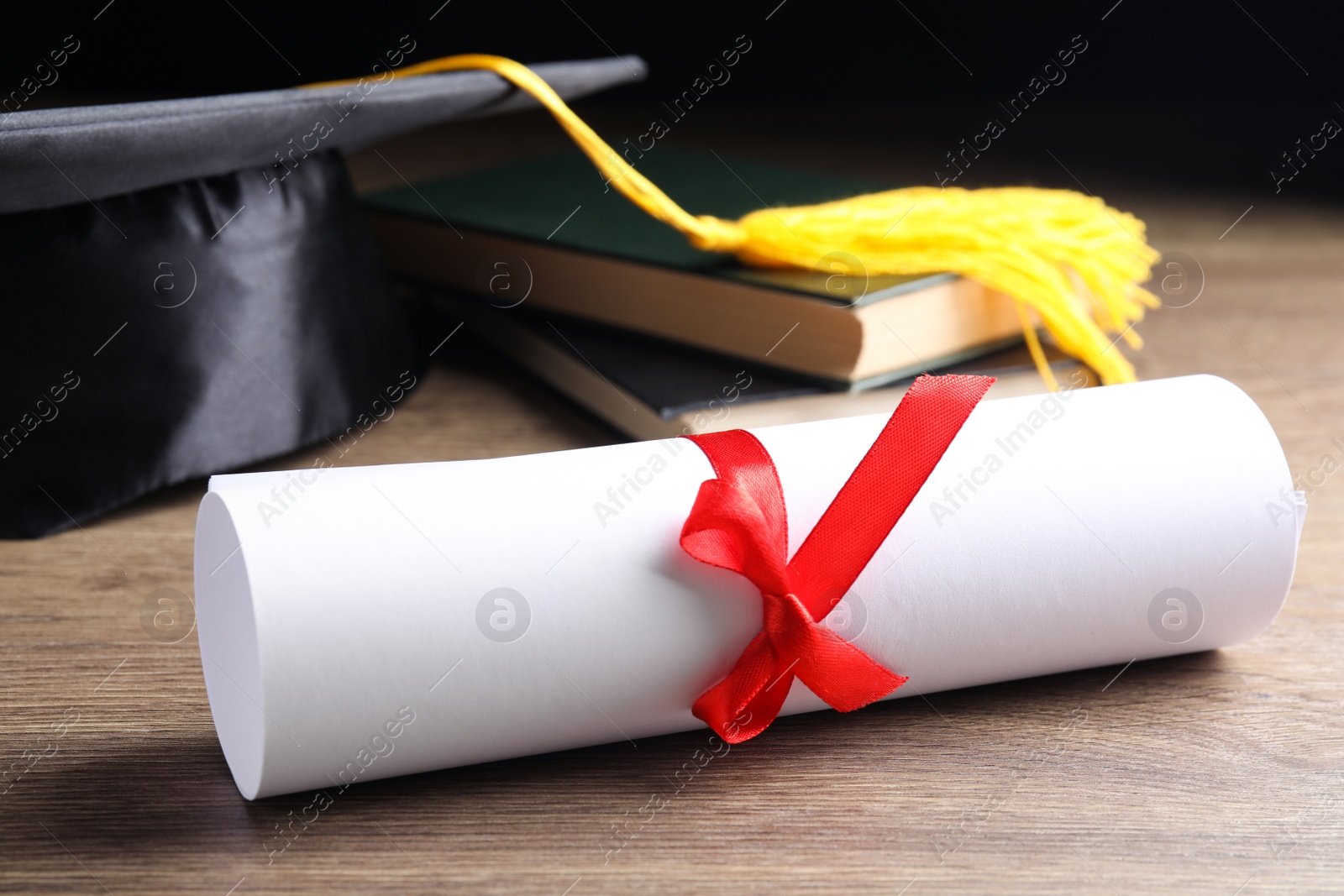 Photo of Graduation hat, books and student's diploma on wooden table