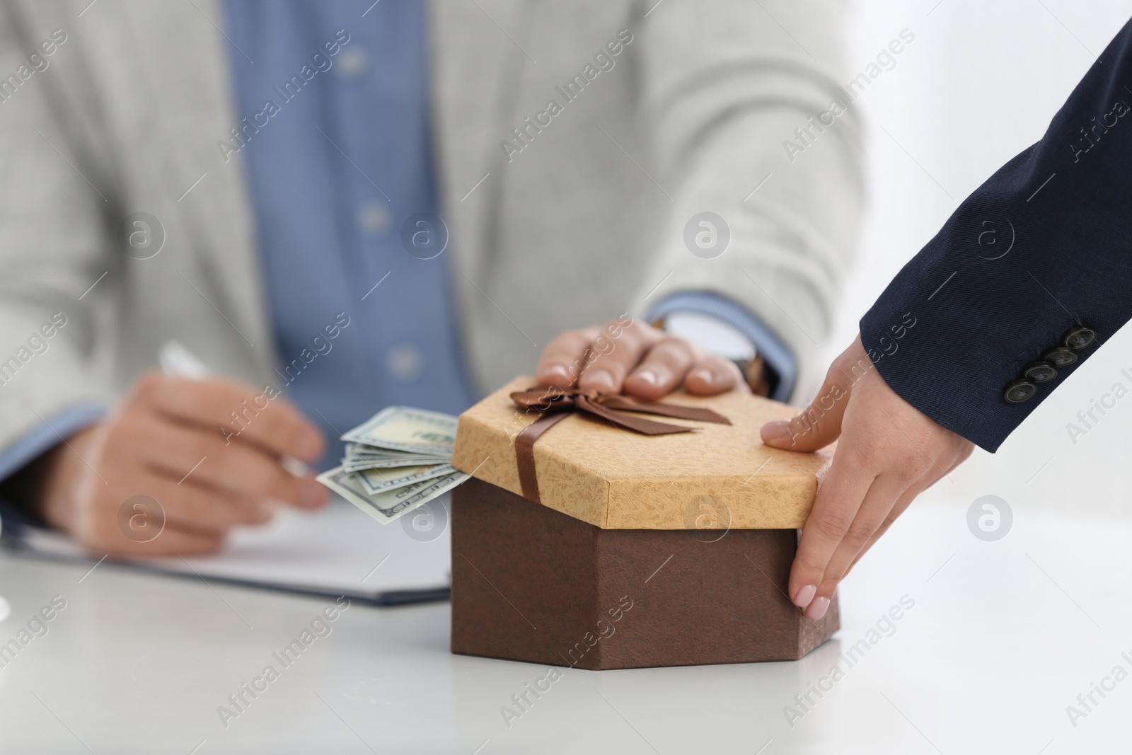 Photo of Woman giving bribe to man at table in office, closeup