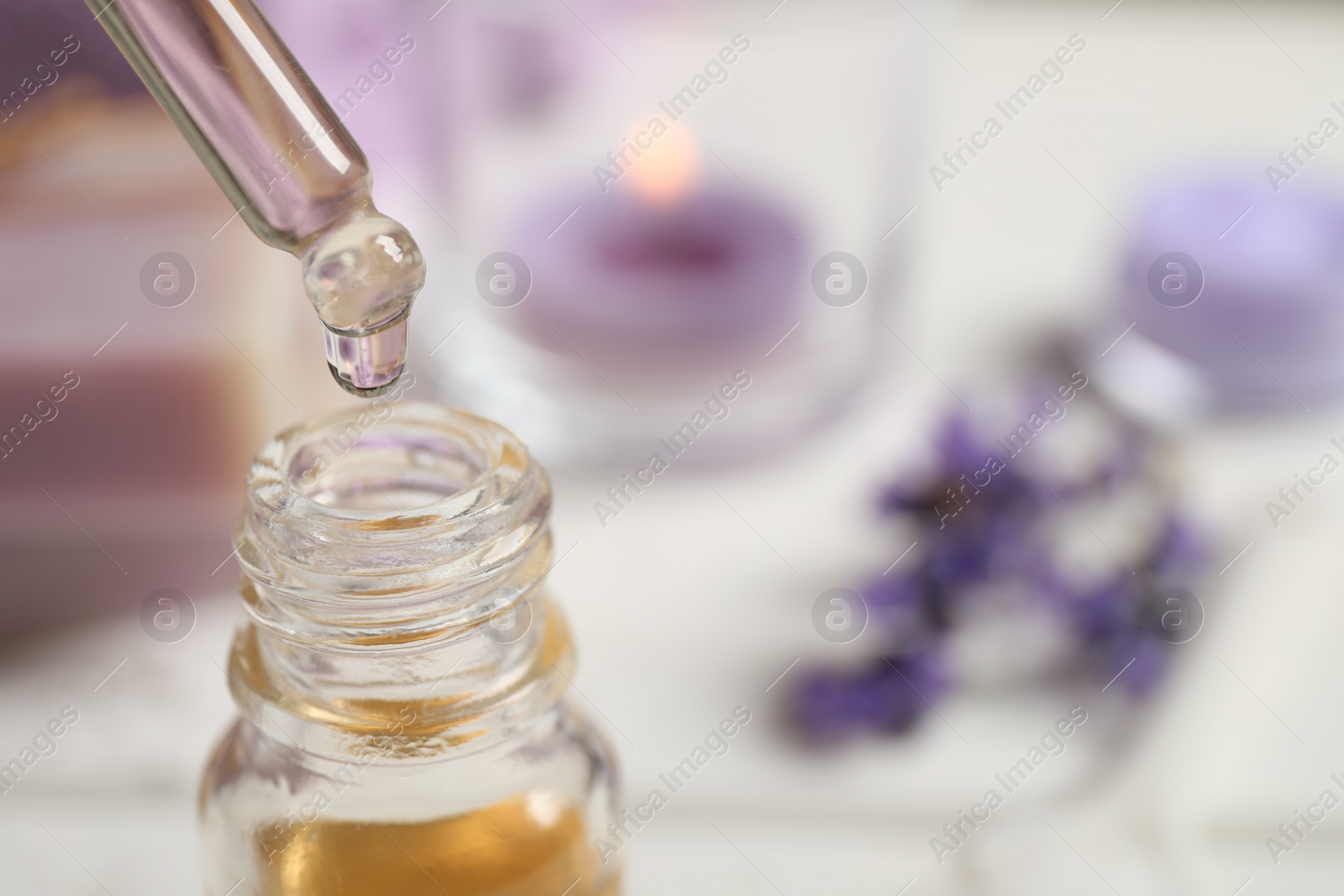 Photo of Dripping lavender essential oil into bottle, closeup. Space for text