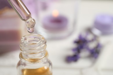 Photo of Dripping lavender essential oil into bottle, closeup. Space for text