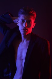 Photo of Sexy young man on dark background in neon lights