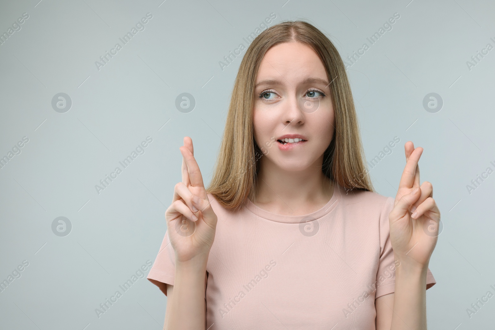 Photo of Woman crossing her fingers on grey background, space for text