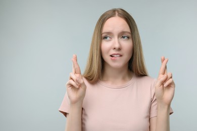 Photo of Woman crossing her fingers on grey background, space for text