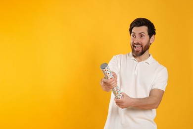Photo of Emotional man with party popper on yellow background. Space for text
