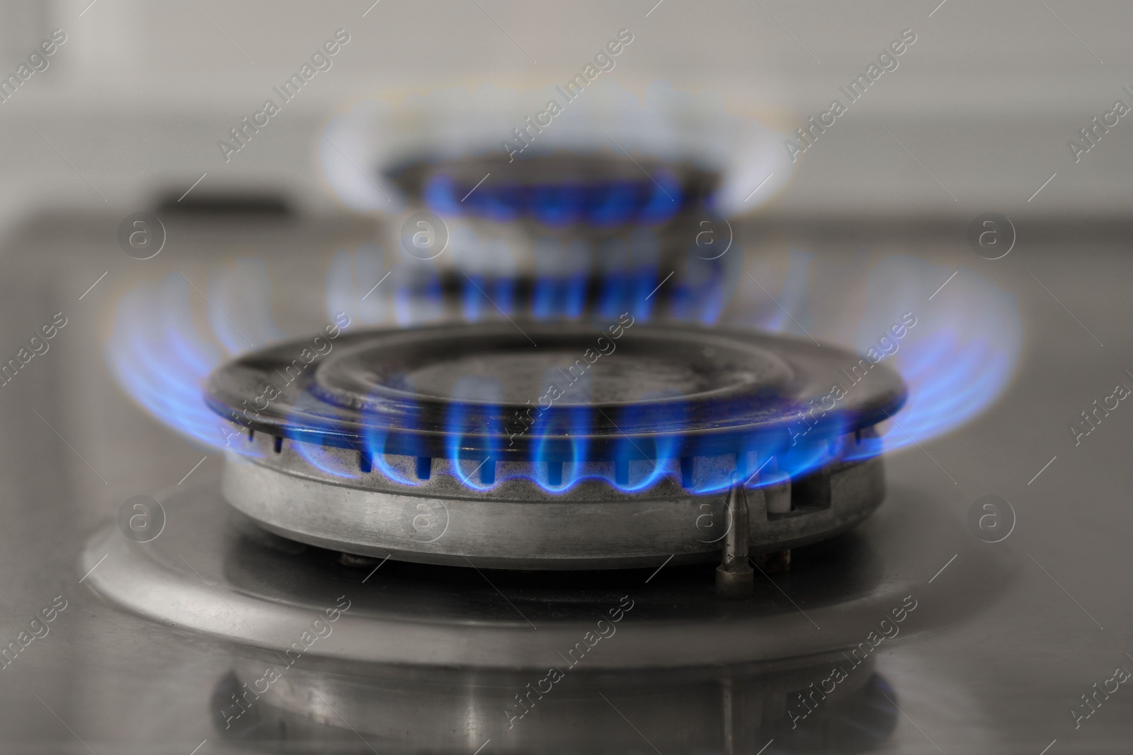 Photo of Gas burner with burning flame on cooktop, closeup