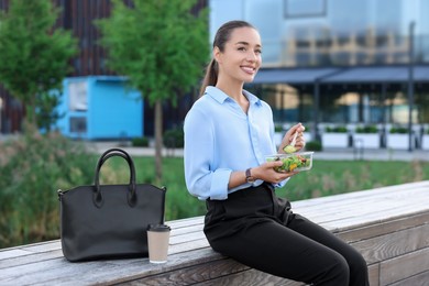 Smiling businesswoman eating lunch during break outdoors