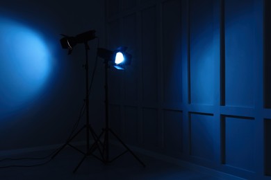 Photo of Bright blue spotlights near wall in dark room, space for text