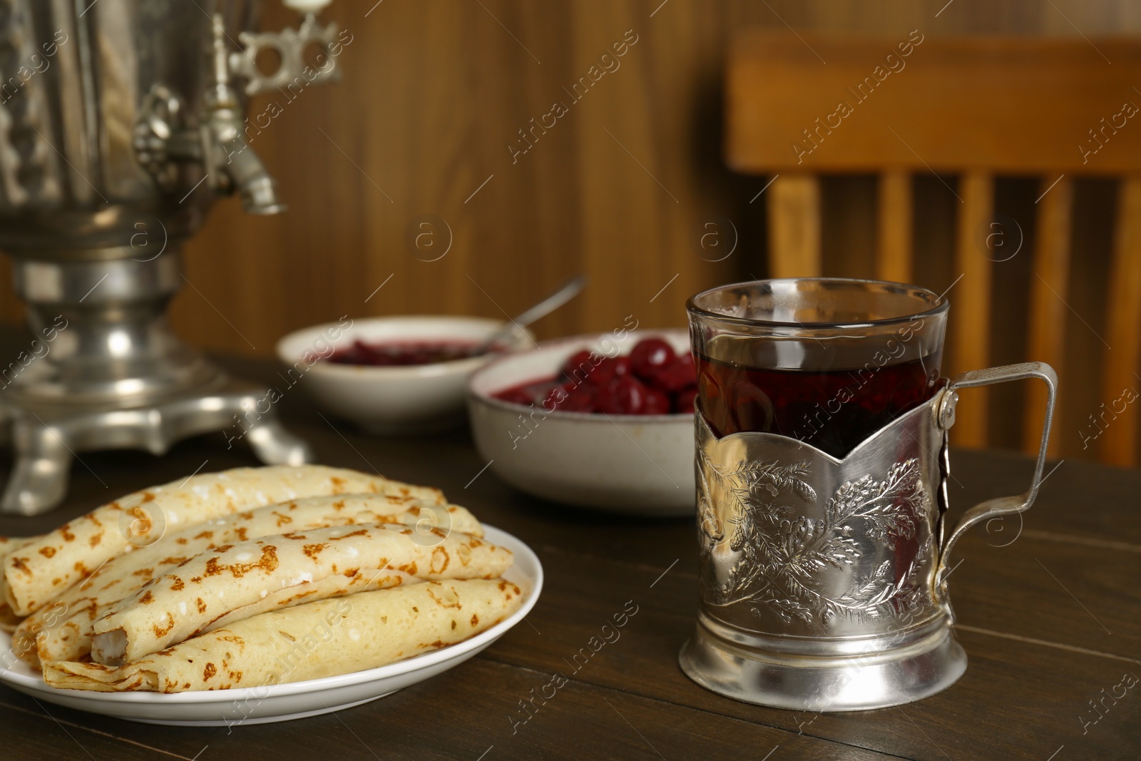 Photo of Vintage samovar, cup of hot drink and snacks served on wooden table. Traditional Russian tea ceremony