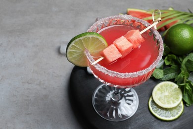 Photo of Cocktail glass of delicious fresh watermelon juice, lime and mint on grey table. Space for text