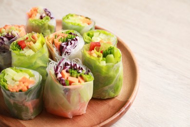 Photo of Plate with different delicious spring rolls wrapped in rice paper on white wooden table, closeup. Space for text