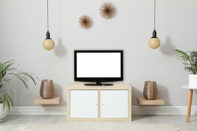 Modern TV set near white wall in living room