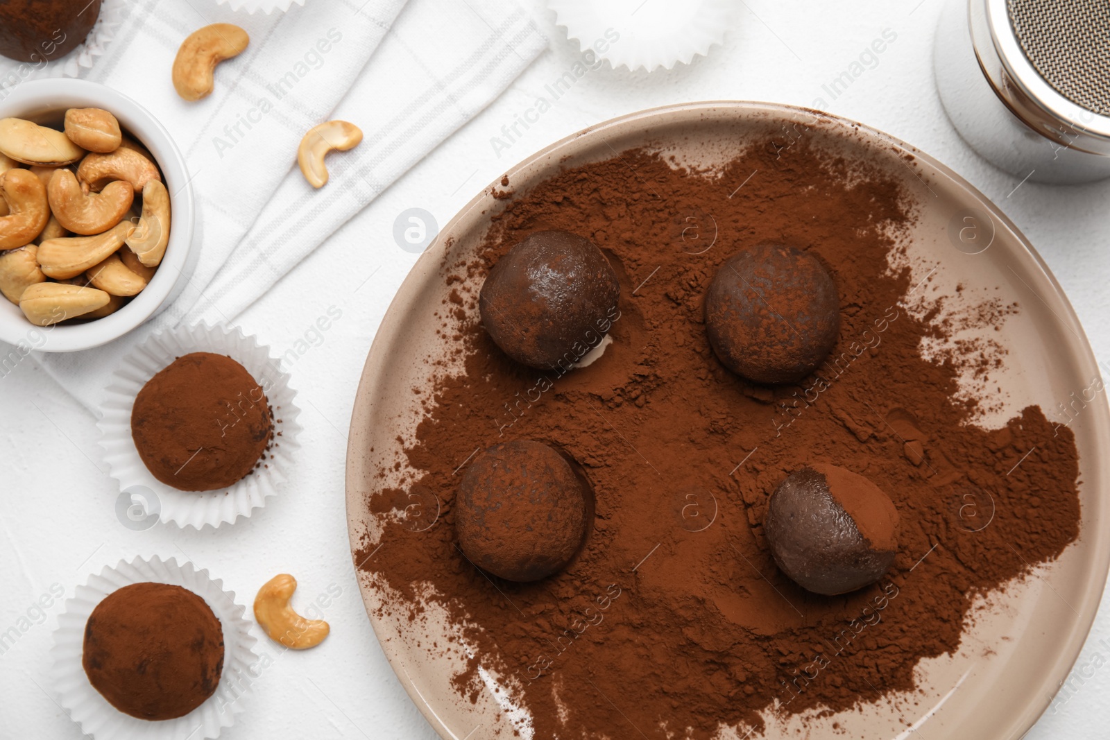 Photo of Delicious chocolate truffles with cocoa powder and nuts on white table, flat lay