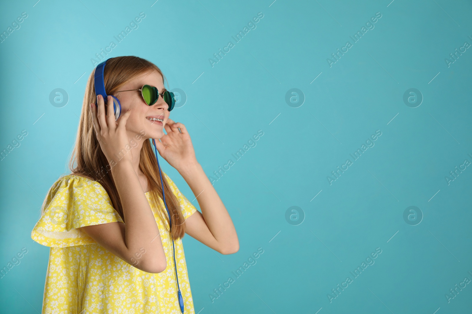 Photo of Teenage girl enjoying music in headphones on color background. Space for text