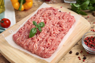 Photo of Raw chicken minced meat with basil and spices on wooden table, closeup