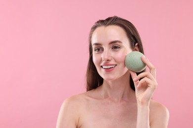 Happy young woman with face sponge on pink background. Space for text