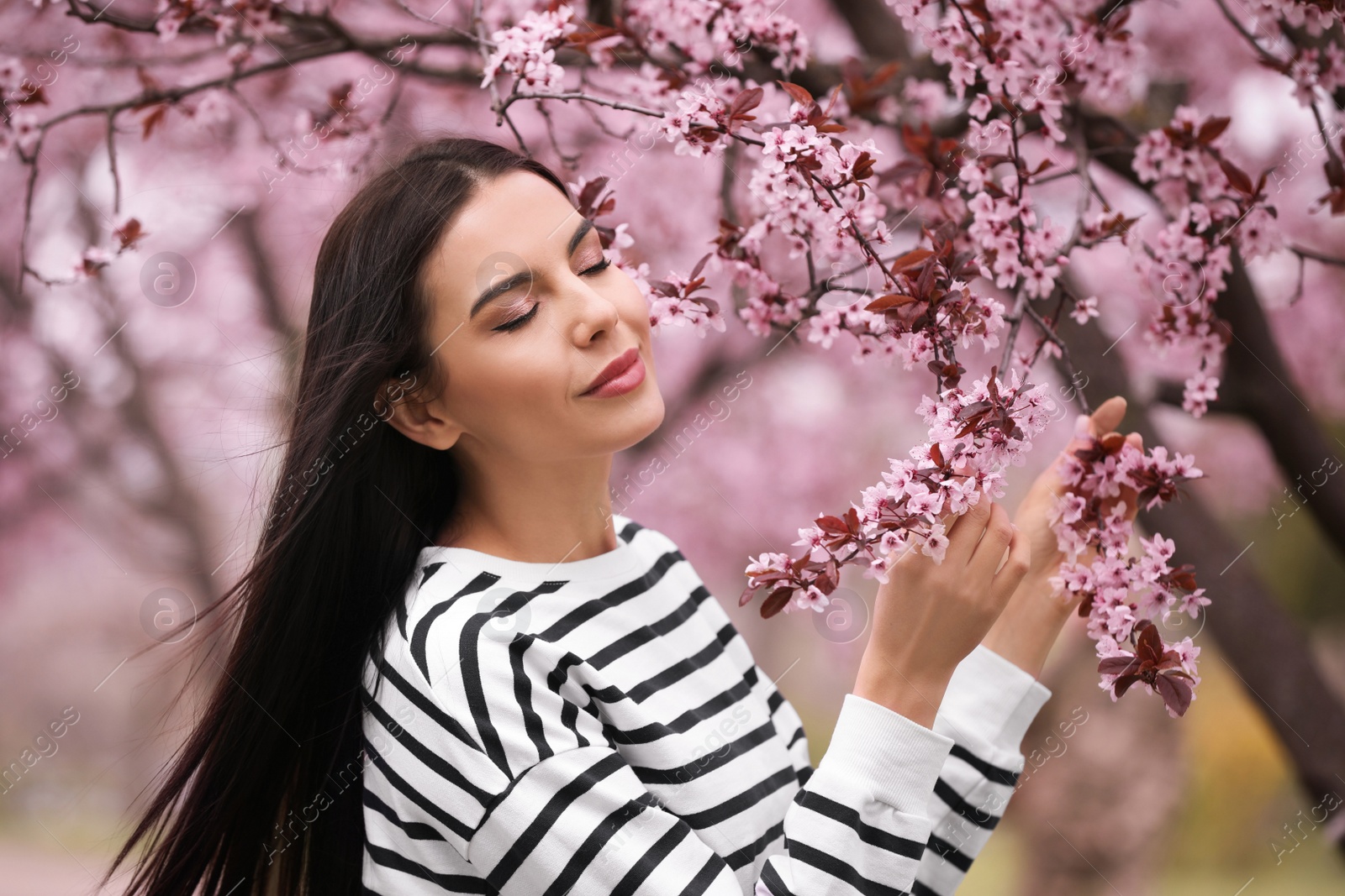 Photo of Pretty young woman near blooming tree in park. Spring look