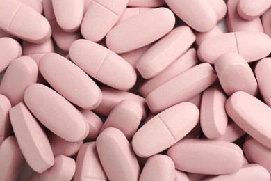 Photo of Pink vitamin capsules as background, top view