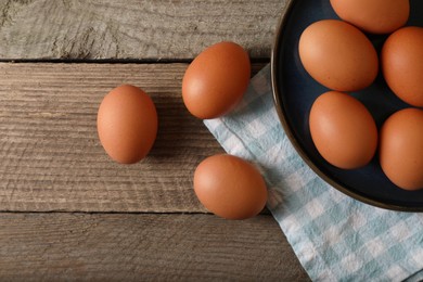 Raw brown chicken eggs on wooden table, flat lay. Space for text