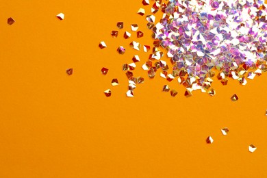 Photo of Pile of shiny glitter on orange background, flat lay. Space for text