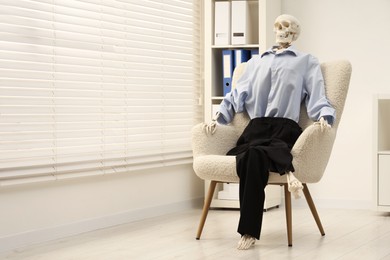 Waiting concept. Human skeleton sitting in armchair at office, space for text