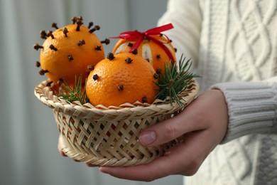 Photo of Woman with pomander balls made of fresh tangerines and cloves on light background, closeup