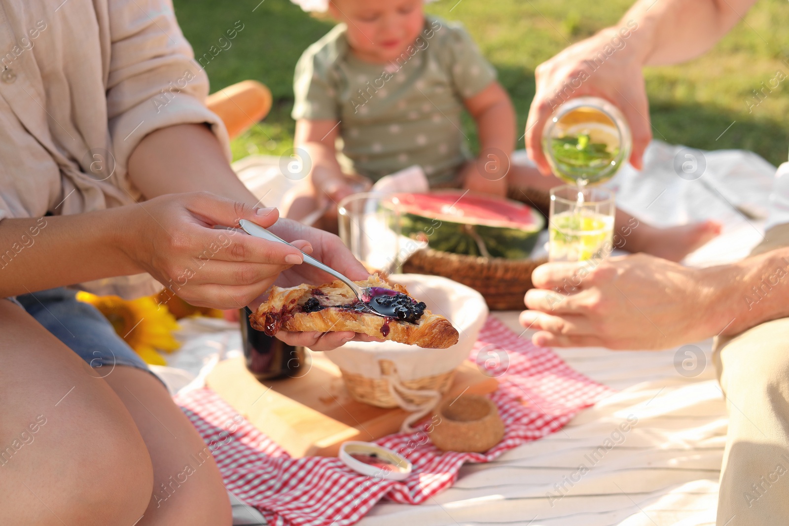 Photo of Family with cute child having picnic on sunny day in garden, closeup