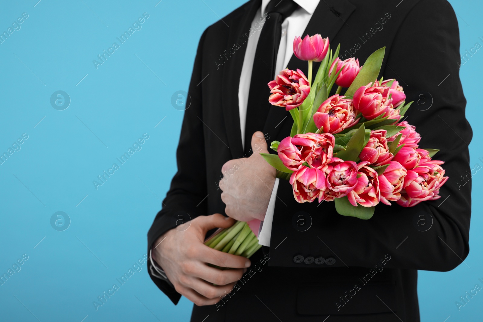 Photo of Man with beautiful bouquet on light blue background, closeup