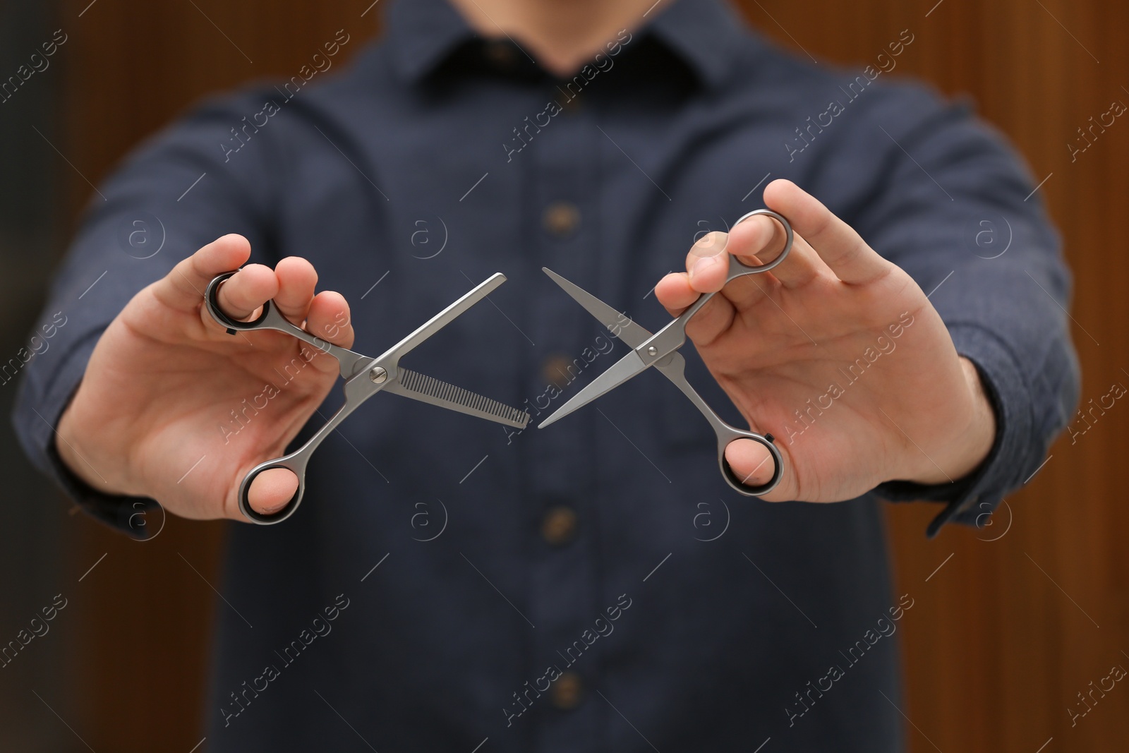 Photo of Hairstylist holding professional scissors in beauty salon, closeup