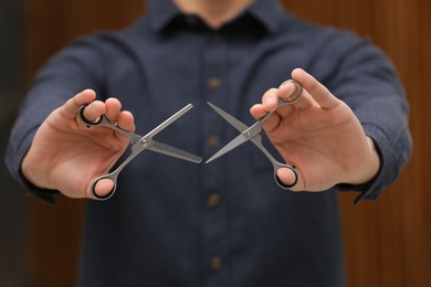 Hairstylist holding professional scissors in beauty salon, closeup