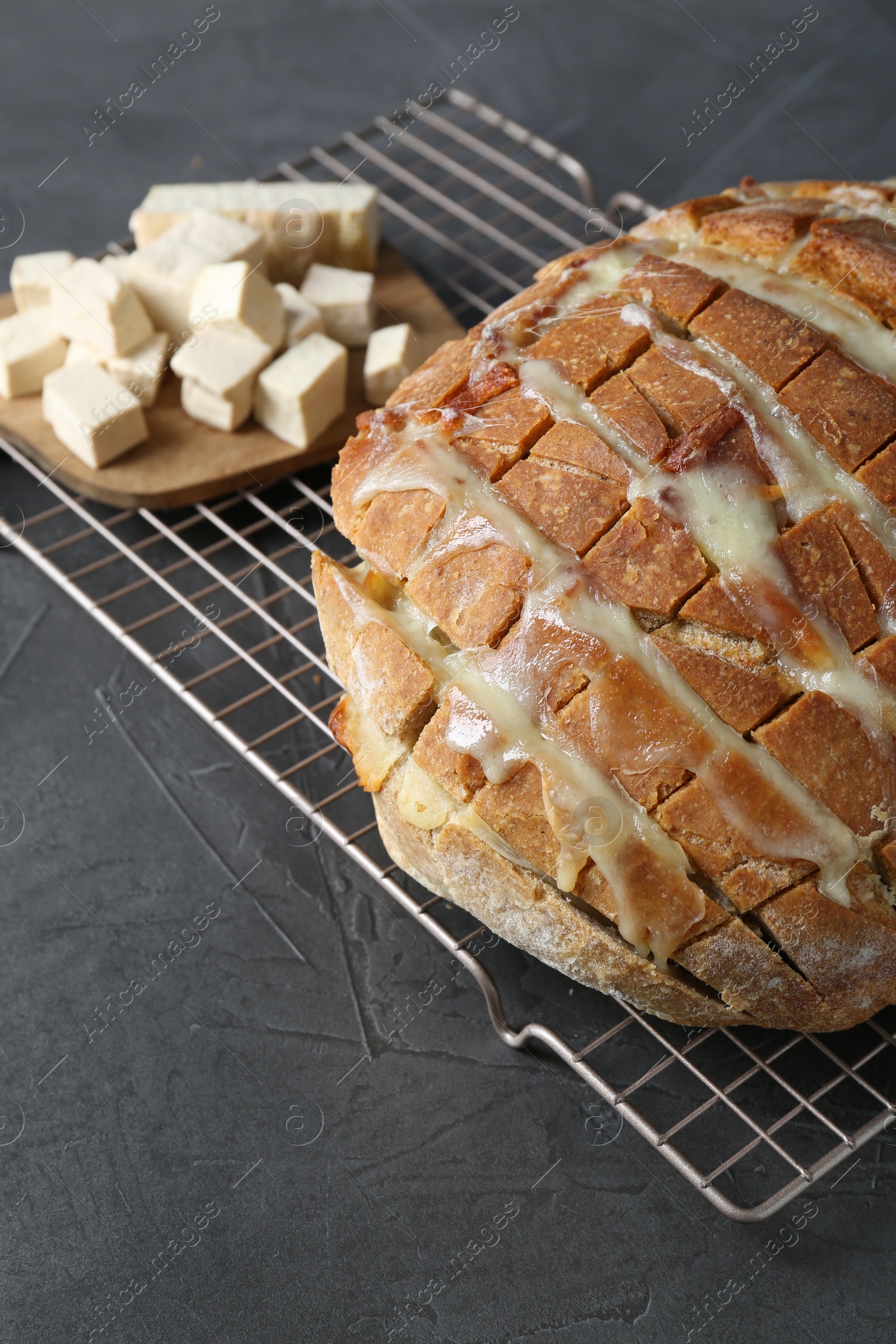 Photo of Freshly baked bread with tofu cheese on black table, closeup