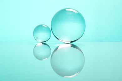 Transparent glass balls on mirror surface against turquoise background