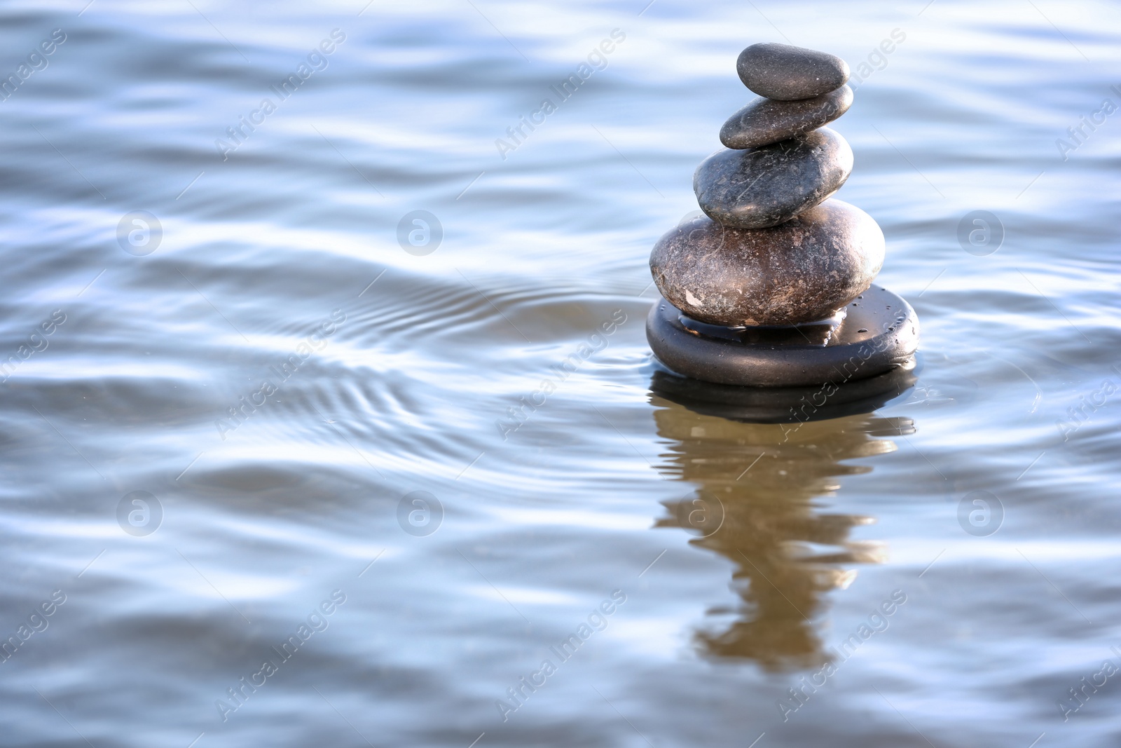 Photo of Stack of dark stones in sea water, space for text. Zen concept